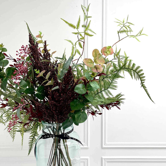 Winter faux foliage arrangement in apothecary vase