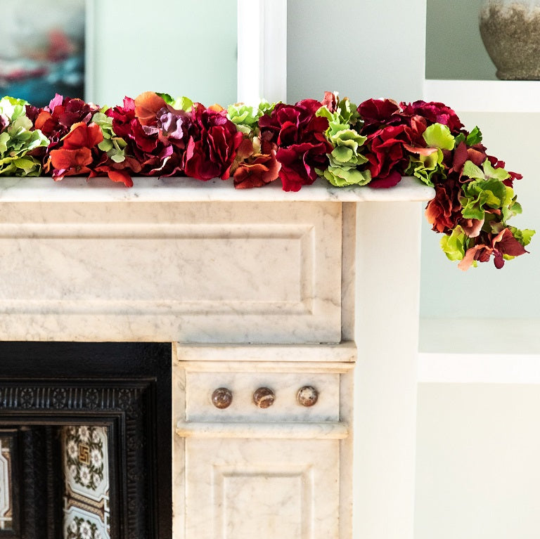 Red and green faux hydrangea garland on mantle